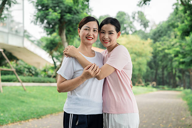 istock A mother and daughter are hugging each other in a park with trees and greenery around them 2227796568