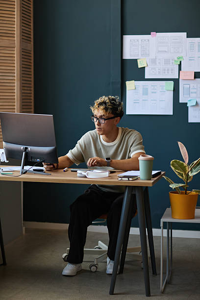 istock Young Adult Caucasian Man Working at Computer in Modern Office Environment 2227805720