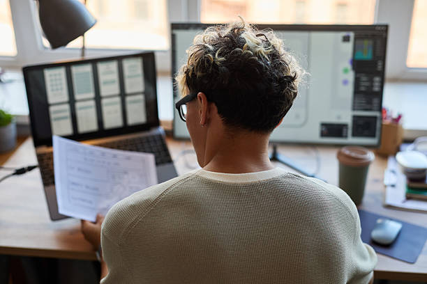 istock Young Adult Caucasian Man Reviewing Wireframe Designs While Working Remotely 2227809291