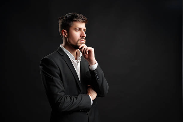 Thoughtful man in a suit posing against a dark background during a studio session
