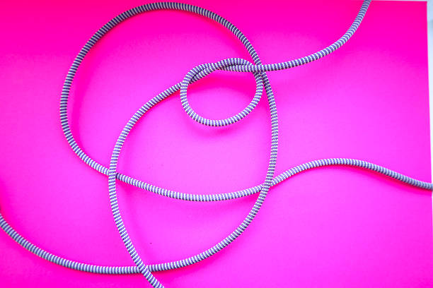 istock A light-colored cord with a fine pattern is chaotically spread across a bright pink background, forming interesting curves and knots. This composition creates a dynamic and appealing visual effect. 2227810657