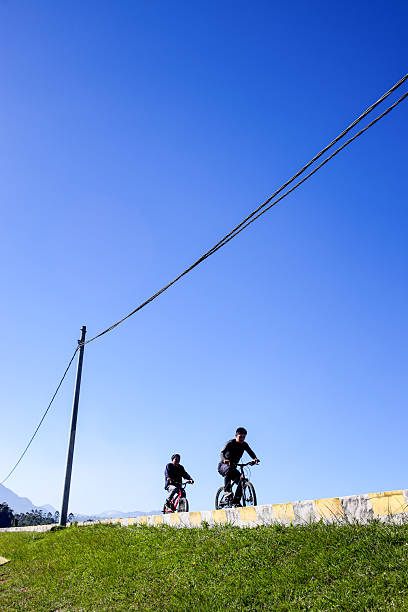 Two Young Men Cycling on a Sunny Day, Enjoying an Outdoor Adventure Under a Clear Blue Sky