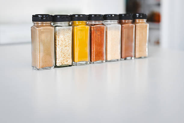 glass jars of garlic, onion, turmeric, paprika, ginger, garam masala and chinese five spice lined up on a kitchen countertop, perfect for cooking, food prep and kitchen lifestyle themes