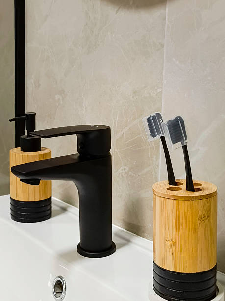 istock Toothbrushes and a bottle for liquid soap stand on the sink. Modern bathroom interior. Close-up, vertical photo. 2227814562