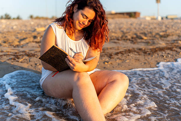 istock Body positive young woman writing on notebook at the beach 2227818902
