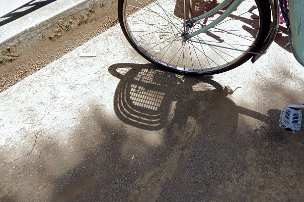 High angle close-up view of the projected shadow of a bicycle over a concrete wall lit by the morning sun