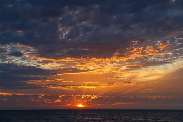 Dramatic ocean sunset with golden rays and glowing clouds, Australia
