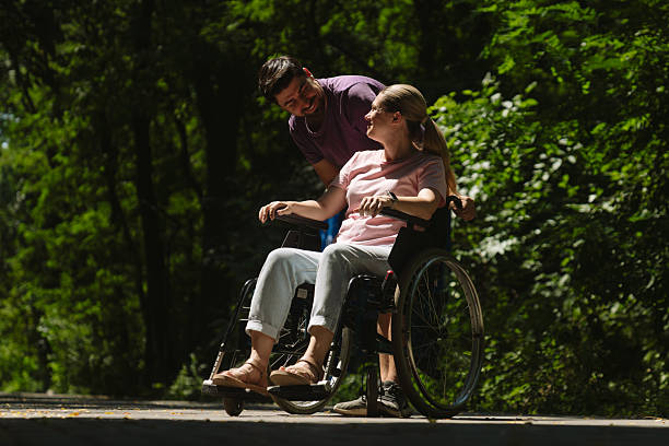 istock Man Assisting Woman in Wheelchair on Sunlit Forest Path 2227825268
