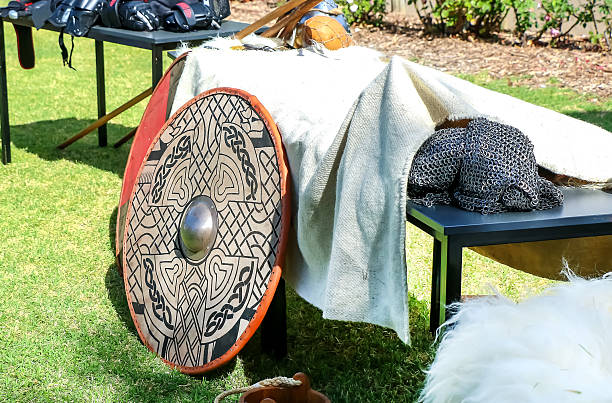 Decorated Viking shield with chainmail armor and medieval weapons displayed outdoors at reenactment event