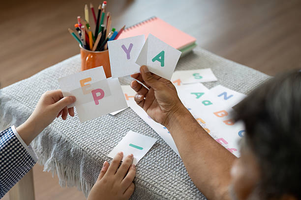 A grandfather helps his grandchild learn letters using colorful flashcards, fostering a fun and interactive educational experience.