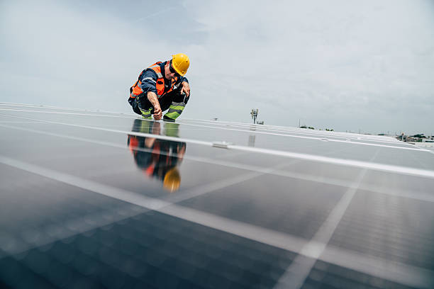 istock Worker performs maintenance on solar panels at rooftop installation site in bright afternoon light 2227832205
