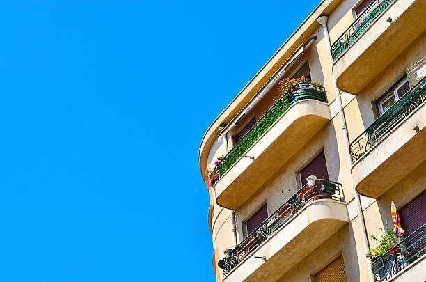 istock Modern residential buildings with multiple balconies adorned with green plants under clear blue sky 2227833566