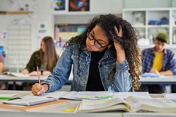 Tired african american student snorts while doing her homework stock photo