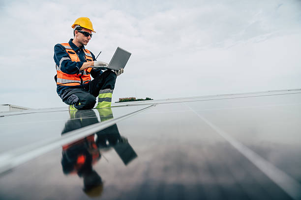 istock Solar technician inspects panels while sitting on rooftop at industrial site during cloudy afternoon 2227835100