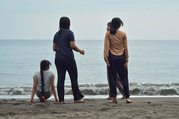 istock Three girls standing, one seated, enjoying beach atmosphere 2227835692