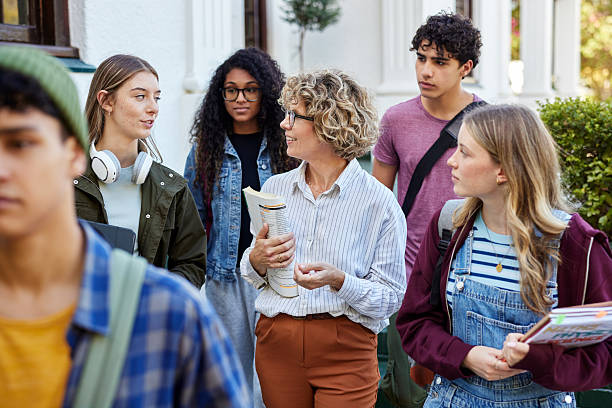 High school teacher walking with multiethnic students outside school