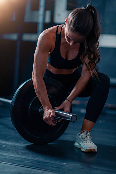 istock Barbell prep with added weights engages a woman, preparing for training to boost strength and fitness in a dedicated gym space. 2227837663