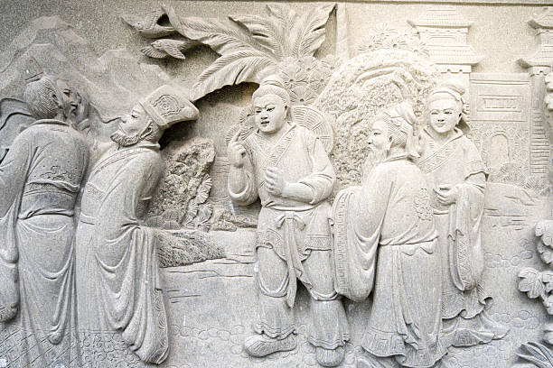 An exquisite statue presenting three women in close embrace, symbolizing unity and grace. The artwork, steeped in classical influence, captures timeless beauty and intricate artistry in monochrome, standing serenely amidst tranquil surroundings.