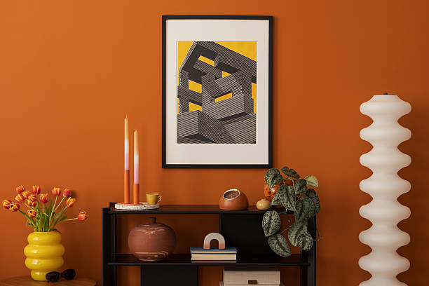 istock Shelf styled with candles, tulips, ceramic decor and graphic print on orange wall in modern home interior. 2227842497