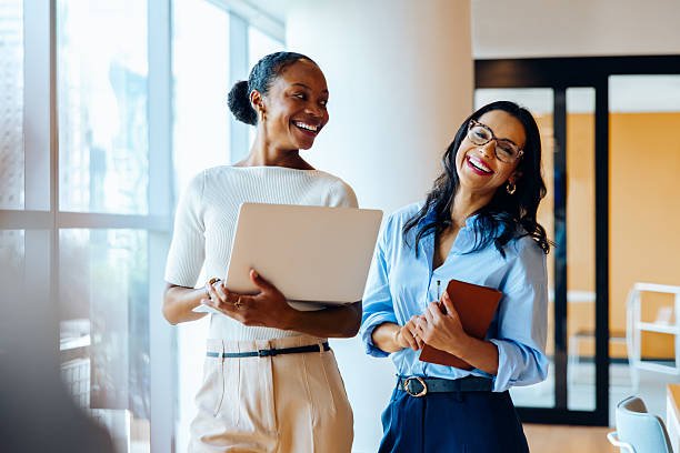 istock Two businesswomen smiling with a laptop and notebook in an office setting 2227842771