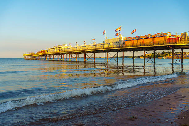 Paignton, UK. 30 July 2025. Paignton Pier at sunset with various signs.