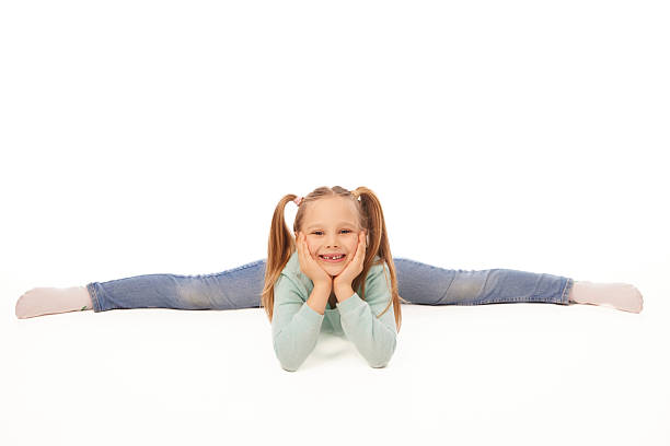 A cheerful young girl reclining on a green background, dressed in casual clothes. Her expression conveys joy and playfulness. Ideal for themes related to children, education, or playful creativity.