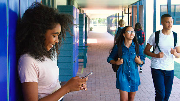 Female High School Student Standing Outside College Building Using Mobile Phone