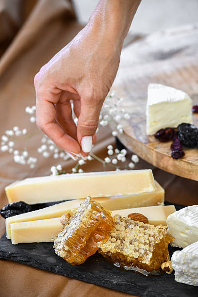 istock Female Finishing Cheese Plate By Adding Dried Fruit On Top 2227845649
