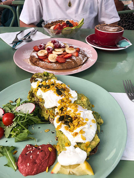 istock Avocado toast with poached eggs and fruit pancakes on outdoor table 2227846025