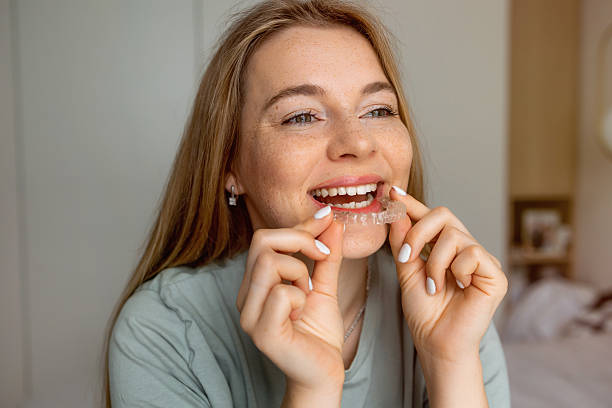 istock Smiling woman holding a clear orthodontic aligner in her hands 2227846040
