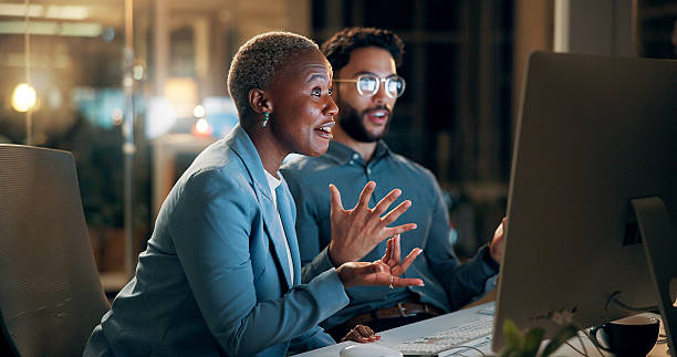 istock Collaboration, computer and night with business people in office together for development or planning. Conversation, feedback or review with man and woman team at work for evening project management 2227848462