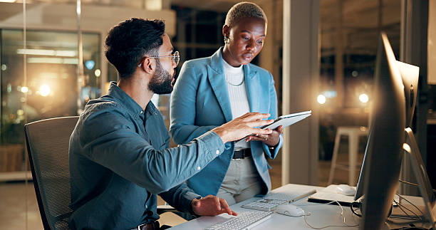 istock Collaboration, night and tablet with business people in office together for development or planning. Computer, feedback or review with employee man and woman in workplace for project management 2227848468