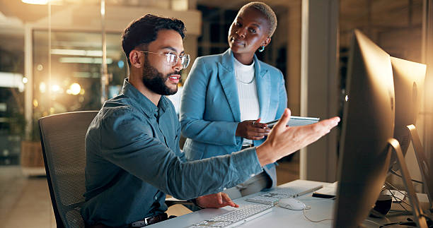 istock Computer, night and question with business people in office together for development or planning. Late, feedback or review with employee man and woman in workplace for project management on tablet 2227848487