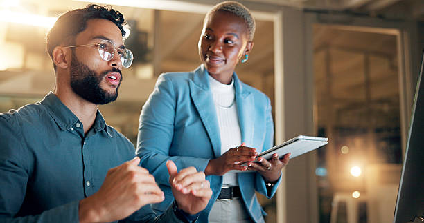 istock Conversation, night and tablet with business people in office together for development or planning. Explain, feedback or review with employee man and woman in workplace for project management 2227848492