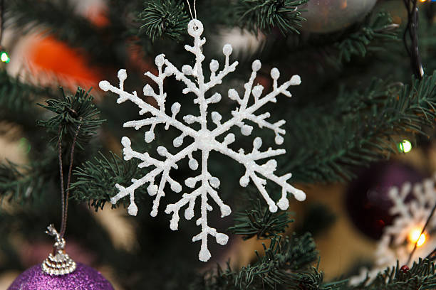 istock A white snowflake ornament hangs on a Christmas tree surrounded by colorful decorations. 2227851599