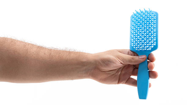 istock Hand with blue hairbrush on white 2227863429