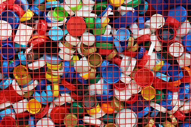 A vibrant and colorful collection of assorted plastic bottle caps is artfully displayed behind a grid structure