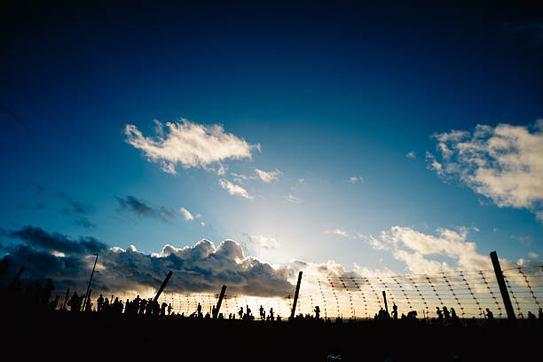 Several unidentified people, silhouetted against clouds and a blue sky in the background. Dramatic sunset. Winter season. Tourists traveling.