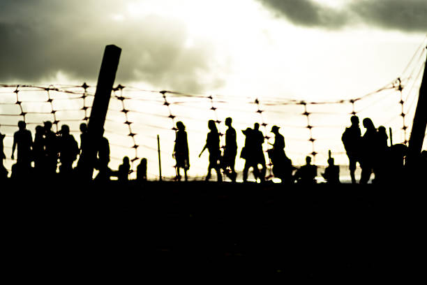 istock Unidentified people blurred in silhouette behind a plastic fence during a dramatic sunset. Winter season. 2227872877