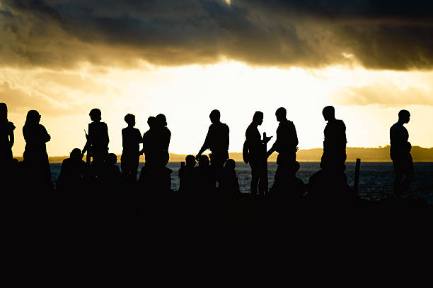Several unidentified people, silhouetted against clouds and a blue sky in the background. Dramatic sunset. Winter season. Tourists traveling.