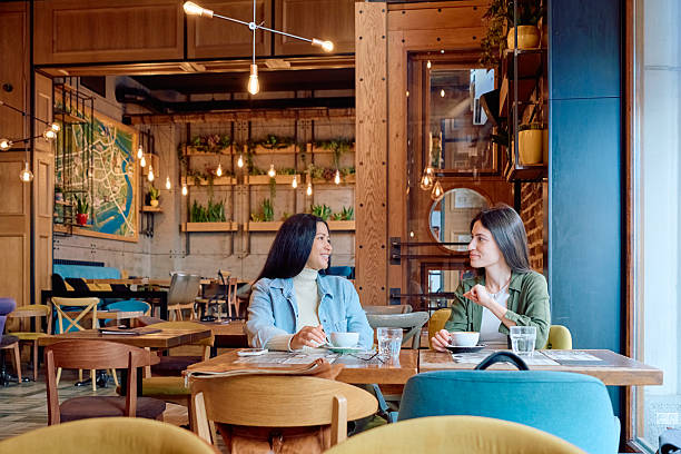 istock Two young women talking and drinking coffee in a trendy cafe 2227876834