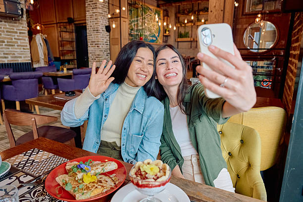 istock Two Young Women Taking a Selfie and Waving in a Restaurant 2227877190