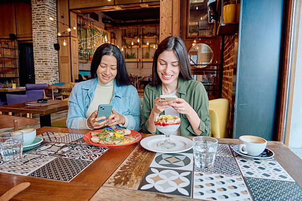 istock Two young women using smartphones while having breakfast in a restaurant 2227877234