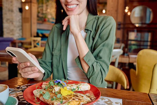 istock Young woman using phone while having breakfast at the restaurant 2227877282