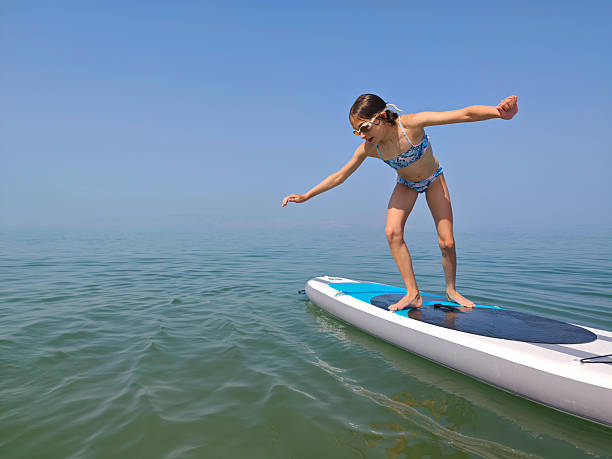 istock Girl Balancing on Paddleboard in Open Water on a Sunny Day. 2227877411