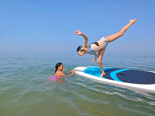 istock Girl Mid-Dive from Paddleboard into Sea on a Bright Summer Day. 2227877413