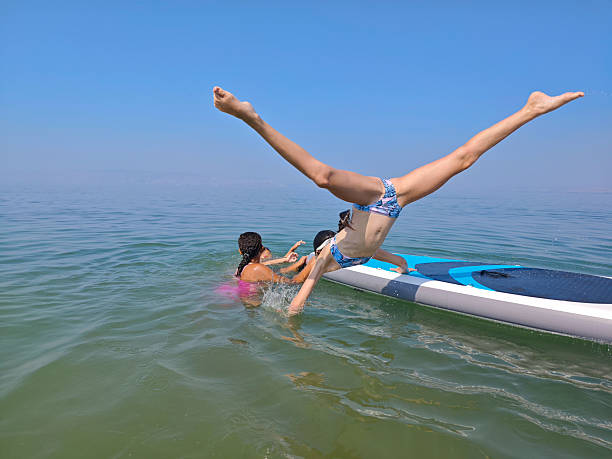 istock Energetic Girl Mid-Flip off Paddleboard on a Bright Summer Day. 2227877416