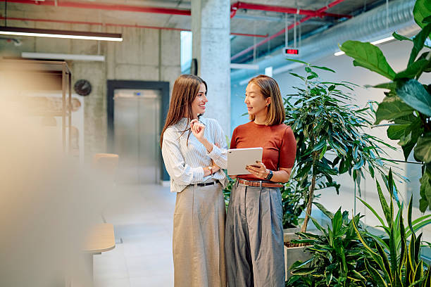 istock Businesswomen using tablet and discussing in modern office with plants 2227879105