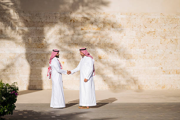 Side view of mid adult and mature business men outside building in Saudi Arabia, handshake, business deal, agreement