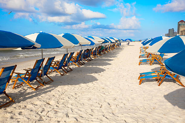 Beach vacation. Patterned beach umbrellas in a row with blue sky and white sand. Combined sky image with chairs in Photoshop to create image. Both images shot in Gulf Shores, Alabama with a Canon EOS Mark V camera.